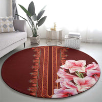 Round burgundy carpet with red geometric panel and pink lily detail at edge