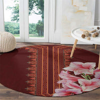 Round burgundy carpet with red geometric panel and pink lilies at bottom right