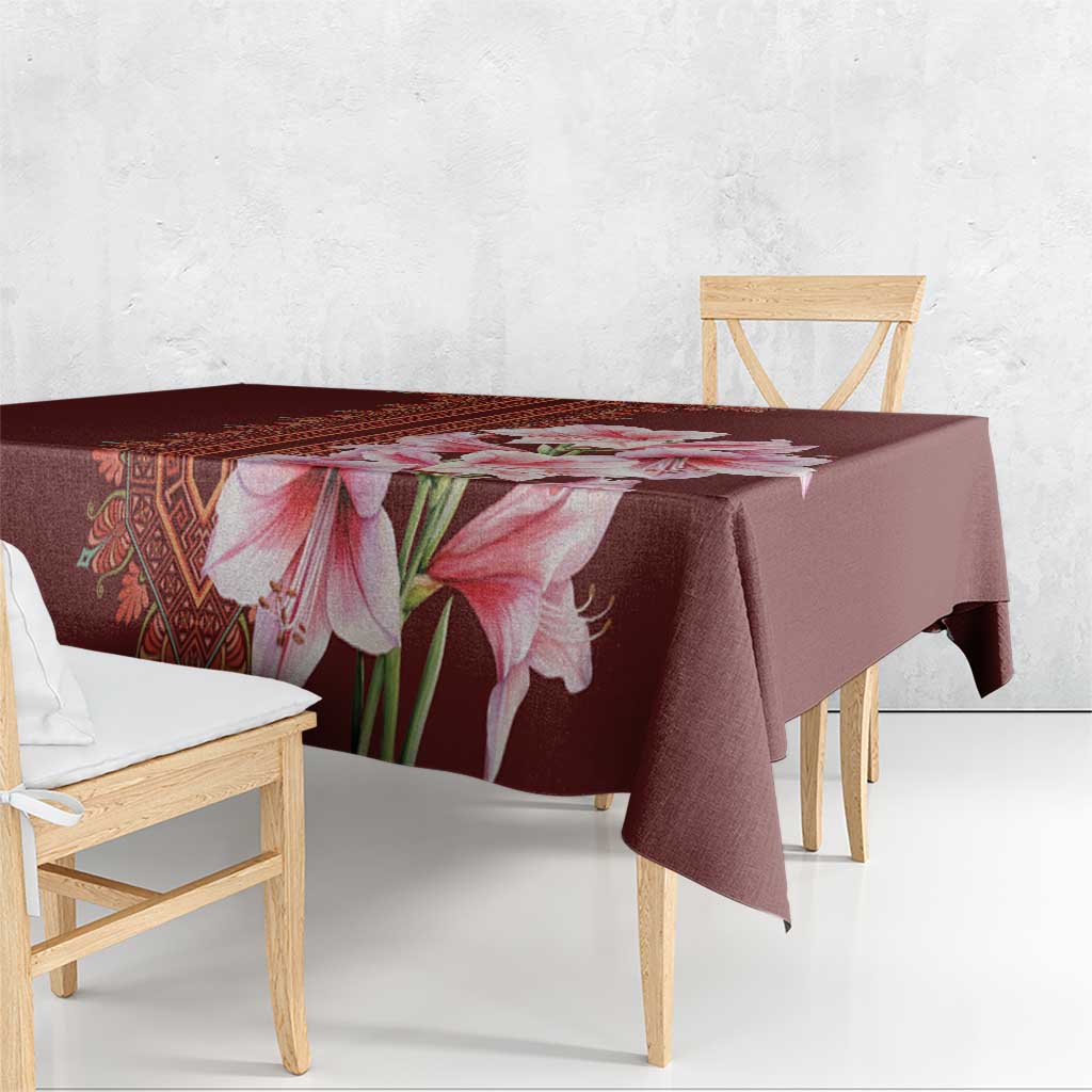 Red tablecloth with large pink lily floral design and patterned stripe at edge