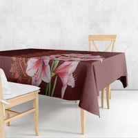 Red tablecloth with large pink lily floral design and patterned stripe at edge