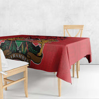 Red tablecloth with coat of arms graphic and green, gold, black Kente-style border