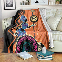 Orange and black throw blanket on bed, featuring African woman face and circular motifs
