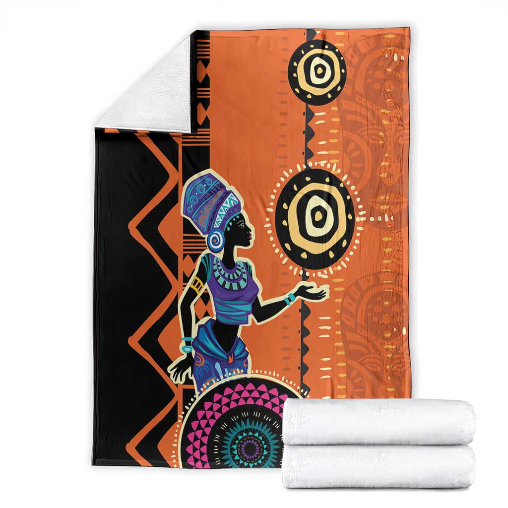 Folded orange and black blanket with African woman graphic and circular mandala motif