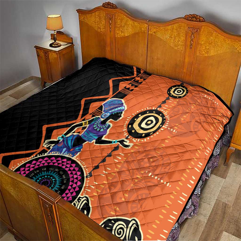 Orange and black quilt blanket on bed with tribal woman print and geometric pattern