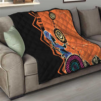 Orange and black quilt blanket draped on a gray sofa with tribal woman artwork