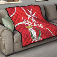 Red quilt blanket with Malta cross design and crest shield on a living room sofa