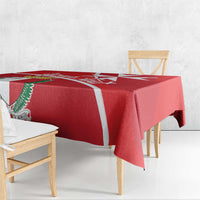 Red printed tablecloth with white Malta cross and coat of arms; drapes over dining table.