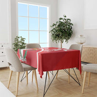 Red Malta cross coat of arms tablecloth with white diagonal band over a dining table.
