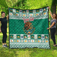 Green quilted blanket held outdoors with Aztec-style border and Mexico crest emblem.