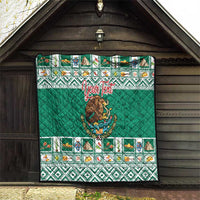 Green quilted blanket hanging on porch with Aztec-style border and Mexico crest.