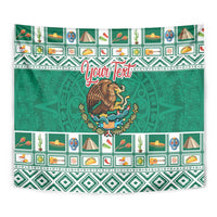 Green tapestry wall hanging showing coat of arms emblem and Aztec-style repeat pattern