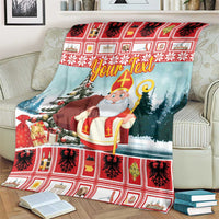 Christmas blanket on sofa, saint holding staff by snowy trees, red plaid border