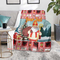 Personalized Christmas blanket on chair, red plaid trim, saint holding staff, snowy trees