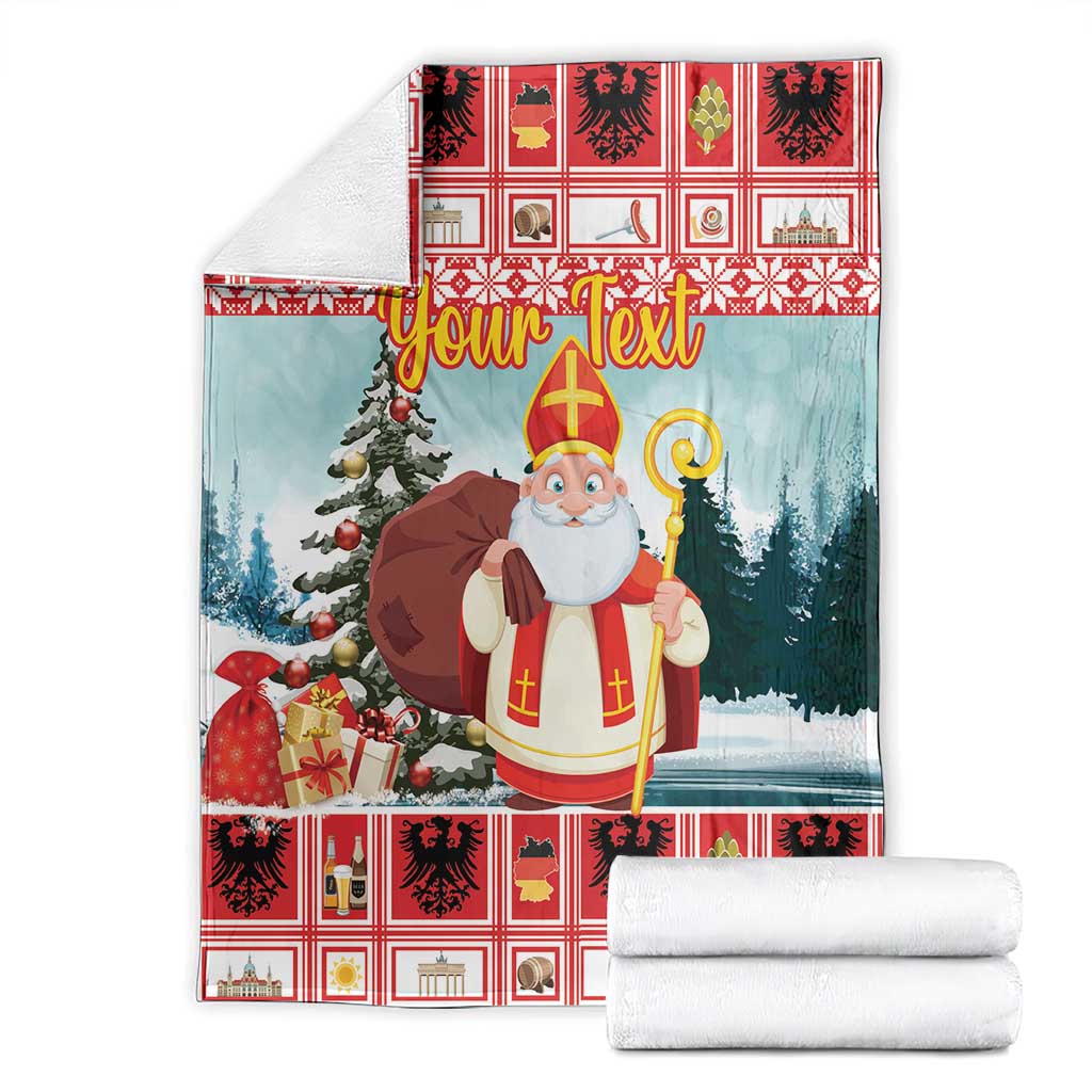 Folded Christmas blanket set with red plaid edge and saint holding staff, blue winter scene