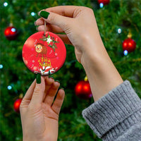 Red round ceramic Christmas ornament with gold hanging loop, held in hand