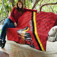 Red quilt blanket held on sofa with black and yellow diagonal stripe and lion graphic