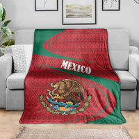 Mexico coat of arms blanket draped on sofa, red folk pattern with central eagle emblem
