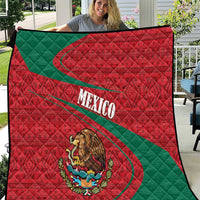 Large Mexico quilt held up, red quilted fabric with green diagonal stripe and coat of arms