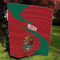 Mexico coat of arms quilt on grass, red and green diagonal bands with quilted diamond texture