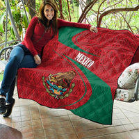 Red and green Mexico quilt spread on patio, quilted texture with coat of arms and stripe