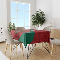 Red and green folk-pattern tablecloth on dining table with chairs around it