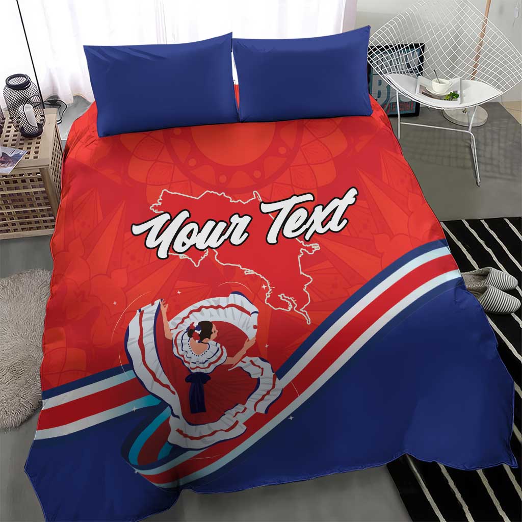 Red and blue bedding set with two blue pillows; duvet shows “Your Text” and Costa Rica dancer artwork