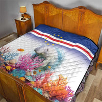 Quilt on bed with Cape Verde flag pattern, stars, and manatee amid coral reef