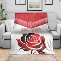 Custom rugby-style blanket on gray sofa showing red/white rose graphic and “YOUR TEXT”