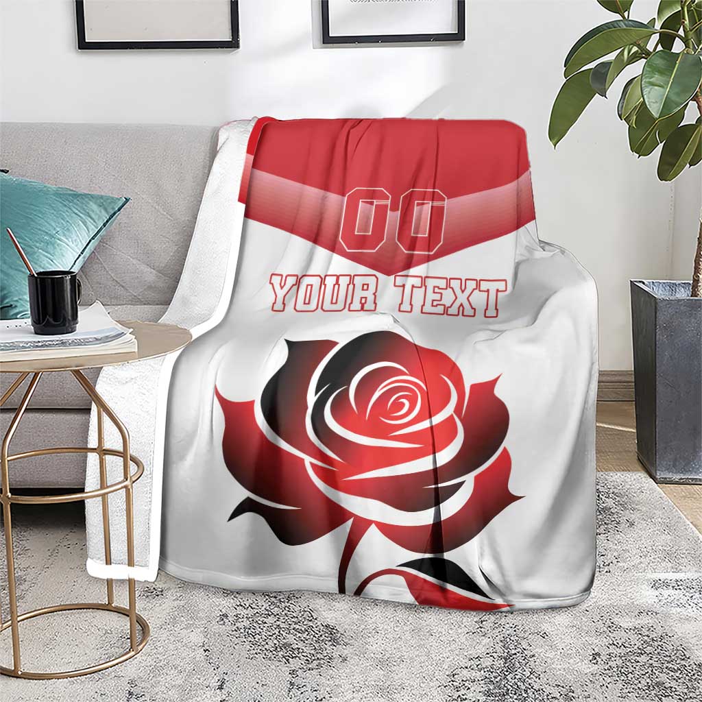 Custom rugby-style blanket on floor with red stripe, rose graphic and “YOUR TEXT”