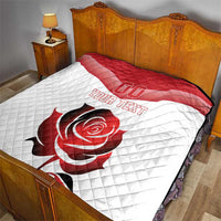 Red and white quilt blanket on bed with diagonal stripe and rose design