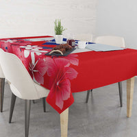 Red hibiscus tablecloth on a dining table with chairs around it