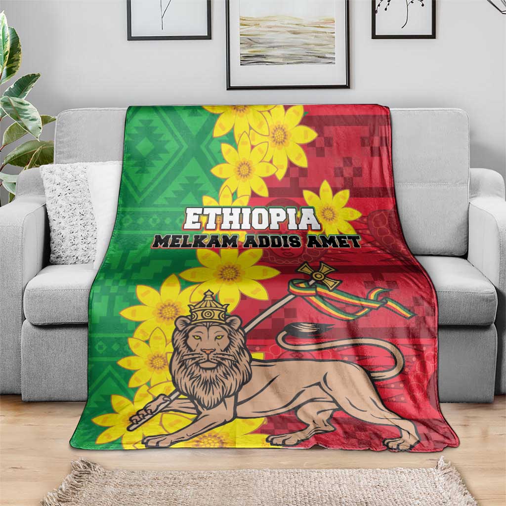 Ethiopia-themed blanket draped over a gray sofa: green/red design, yellow flowers, lion graphic