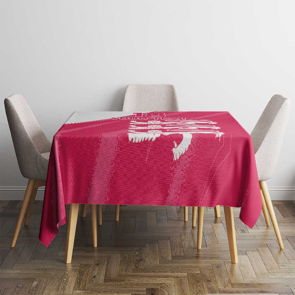 Pink tablecloth with white lion motif on a dining table with four chairs.