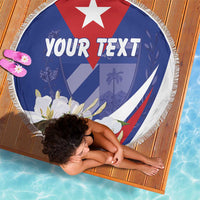 Round blue beach blanket with tassel fringe, red and white emblem and floral print