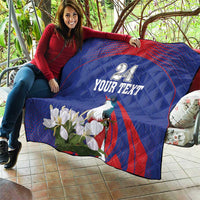 Blue quilt held outdoors with red curve, bird and white flowers, custom text design