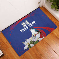 Blue rubber doormat showing “24 YOUR TEXT” text, bird, white flowers, red spiral