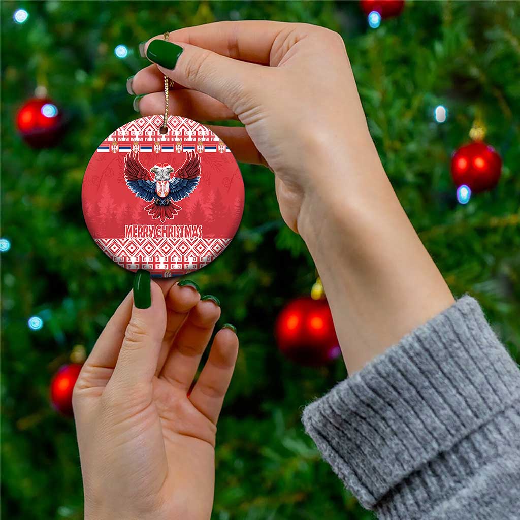 Hand holding red round ceramic ornament with double-headed eagle and Merry Christmas