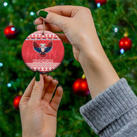 Hand holding red round ceramic ornament with double-headed eagle and Merry Christmas