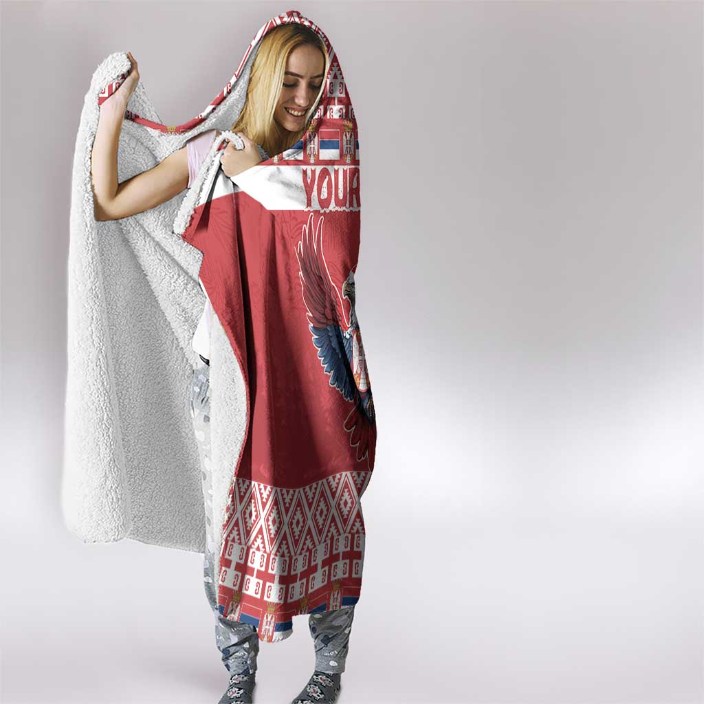 Red and white hooded blanket worn by woman, eagle design visible on front