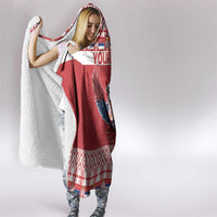 Red and white hooded blanket worn by woman, eagle design visible on front