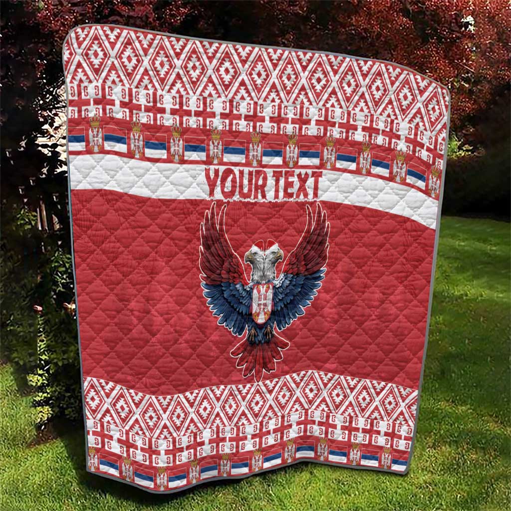 Red quilt on grass with central double-headed eagle and 'YOUR TEXT', patterned border