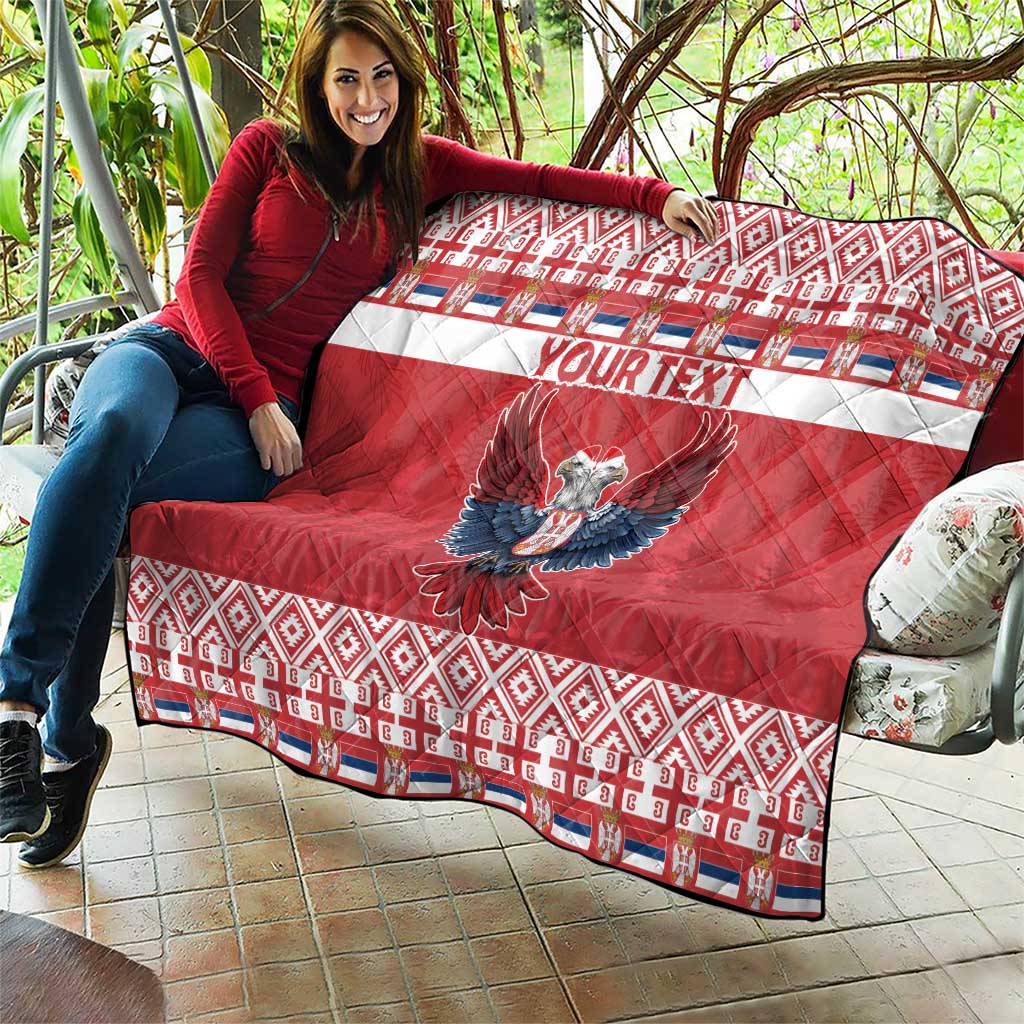 Red quilt on patio with 'YOUR TEXT' and double-headed eagle, quilted geometric trim