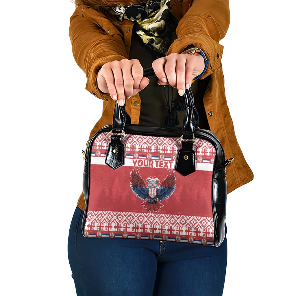 Red and black shoulder handbag with eagle crest and geometric holiday stripe panel