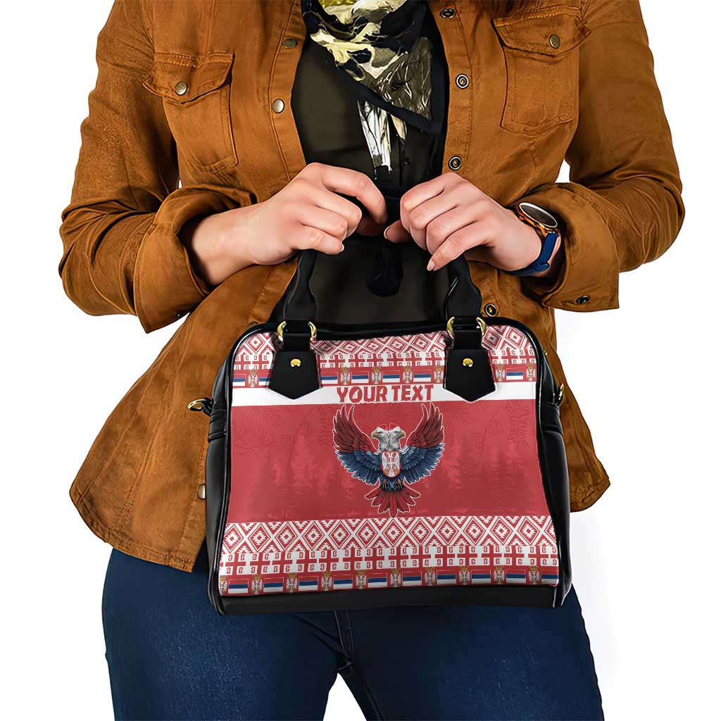 Red and black shoulder handbag with eagle emblem, white/red border pattern, and black straps