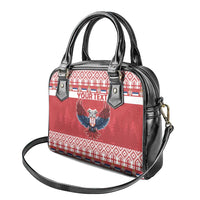 Red and black handbag with eagle crest, geometric border print, and adjustable shoulder strap