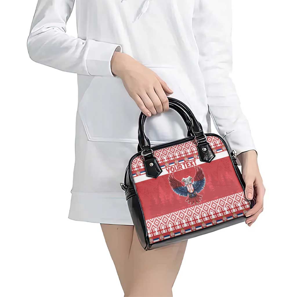 Red and black handbag with eagle emblem, patterned front panel, and black top handles