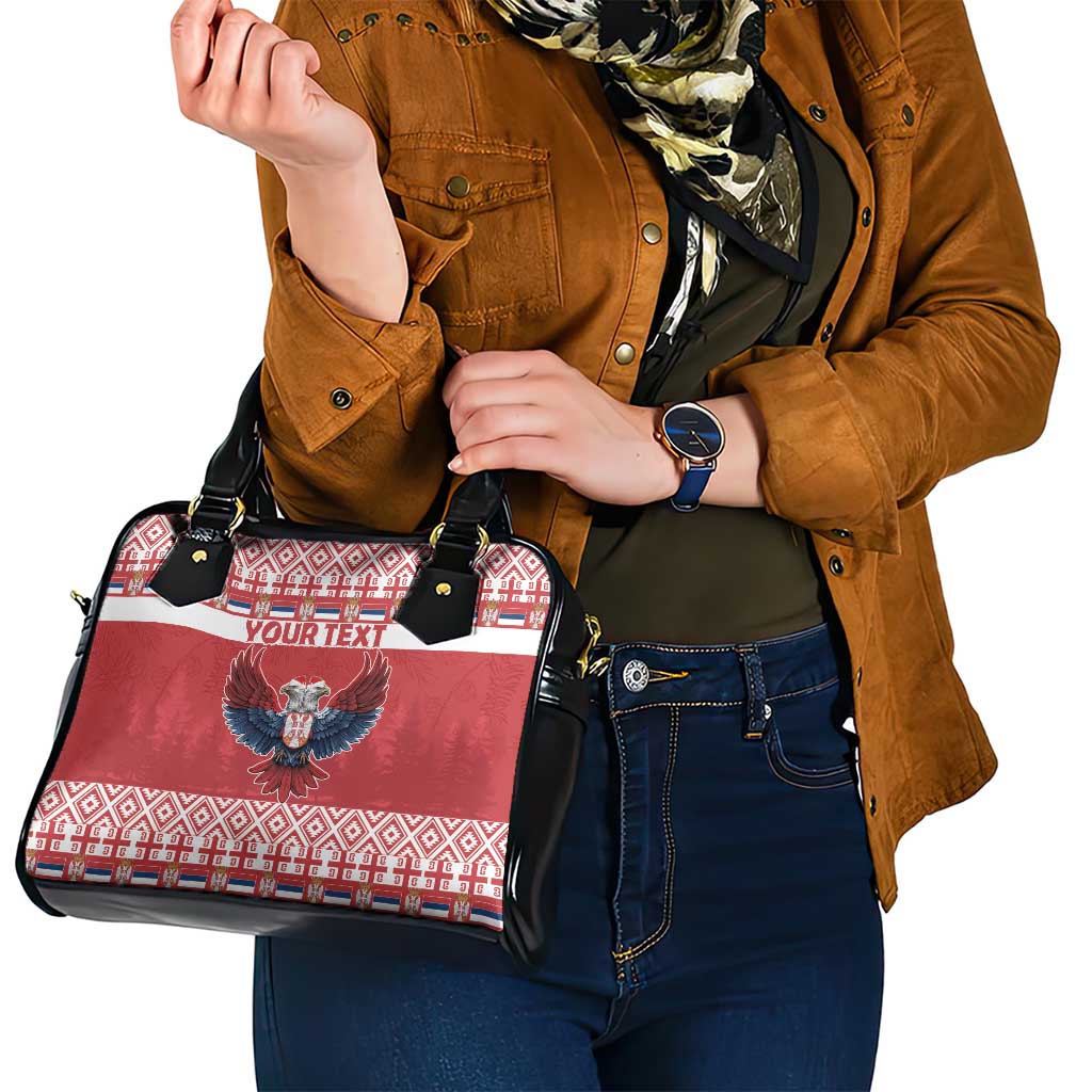 Red and black shoulder handbag with eagle emblem, holiday pattern front, and two top handles