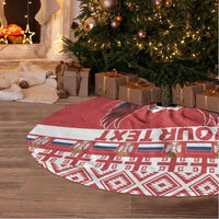 Red round Christmas tree skirt with eagle emblem and white patterned border, fringe