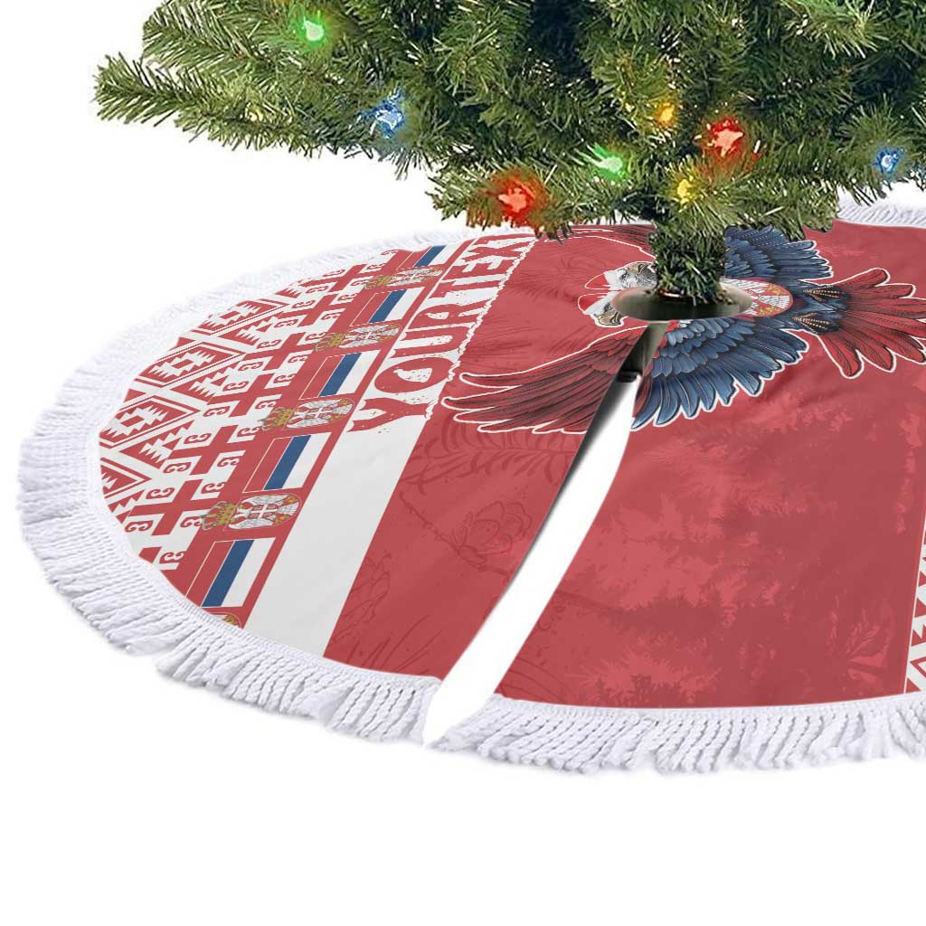 Red round Christmas tree skirt with eagle motif, white geometric panel, and tassel fringe