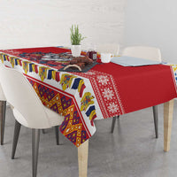 Red tablecloth draped on dining table with colorful folk-style border